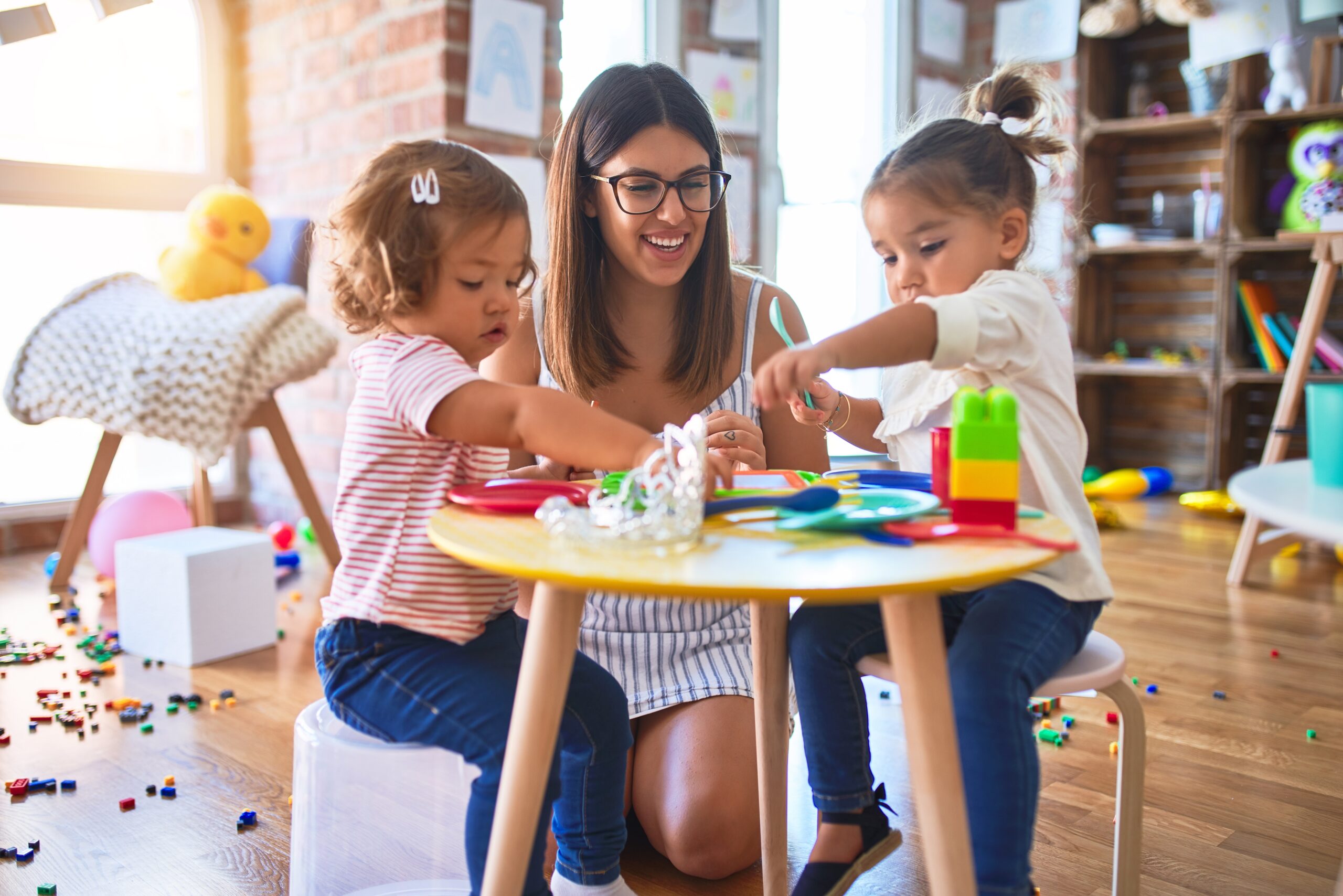 Young beautiful teacher and toddlers playing meals using plastic food and cutlery toy at kindergarten Young beautiful teacher and toddlers playing meals using plastic food and cutlery toy at kindergarten
